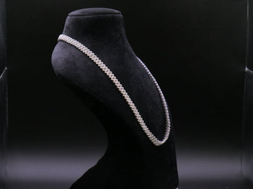 Pearl necklace on a black mannequin bust against a dark background